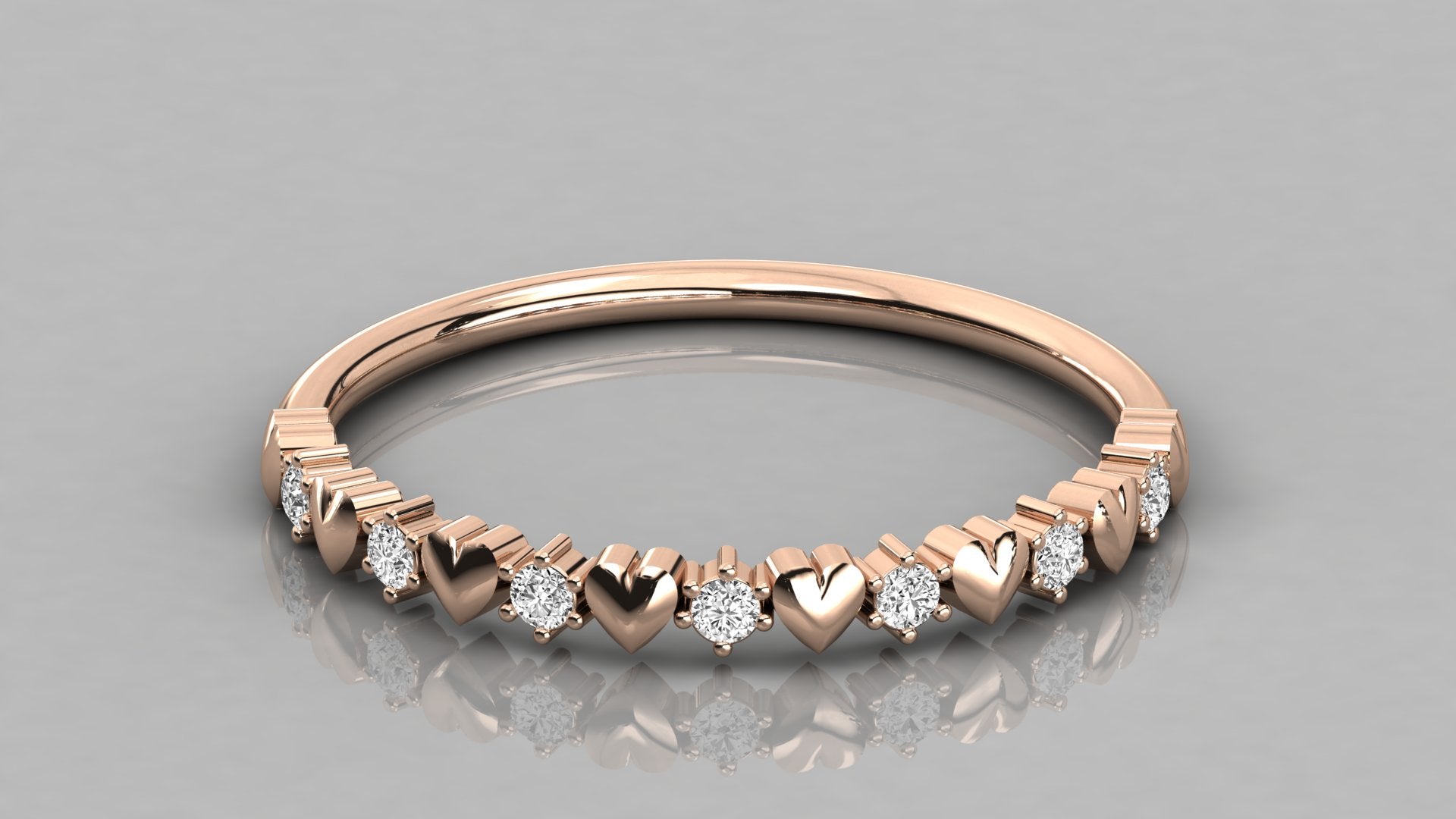 A low-angle perspective view of the Juliette 14k rose gold heart ring, featuring a polished infinity band and seven brilliant lab-grown diamonds.