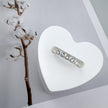 A professional product photograph of the Luna 14K white gold stackable ring with five bezel-set lab-grown diamonds, elegantly displayed on a white heart-shaped stand next to a cotton branch.