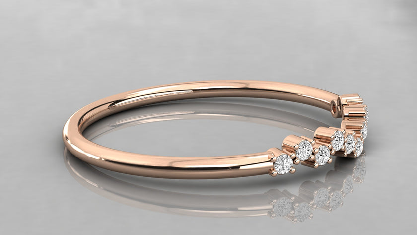 Side perspective of the Lyra rose gold chevron band lying on a surface, highlighting the eleven sparkling ethical diamonds.